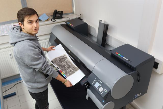 Die Reproduktionen werden im 12-Farb-Verfahren auf einem High-End-Printer produziert. Hier entnimmt Mediengestalter-Azubi Christoph Fiebig ein Exemplar.