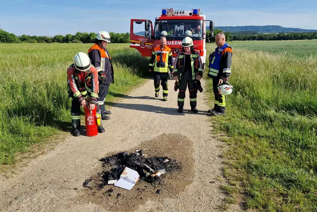 Einsatzkräfte löschen den Stapel der verbrannten Bücher mittels Kleinlöschgerät ab. | Foto: Feuerwehr Brand