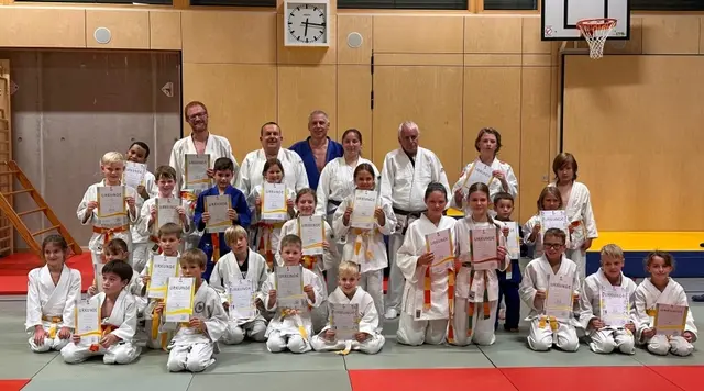 Glückliche Judoka mit Urkunden und neuen Gürteln.