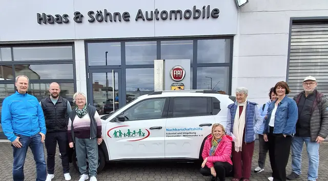 Markus Haas und ehrenamtliche Helfer freuen sich über das E-Auto