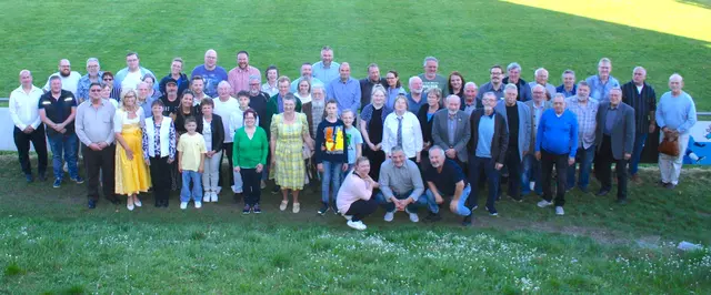 Eine Gruppe von etwa 50 bis 60 Menschen, die sich auf einer Wiese zu einem Gruppenfoto aufgestellt haben. Anlass ist der Festabend des Rassegeflügelzuchtvereins. In einem leuchtend gelben Kleid ist die Eckentaler Bürgermeisterin Ilse Dölle im Vordergrund zu sehen.