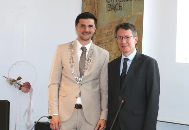 Links der Bürgermeister Sebastian Singer in einem hellen Anzug mit Amtskette. Rechts daneben Manfred Bachmayer. Er trägt einen dunklen Anzug.